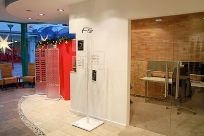 Modernes Optikergeschäft mit Brillenauswahl, Glaswand und weihnachtlicher Dekoration.